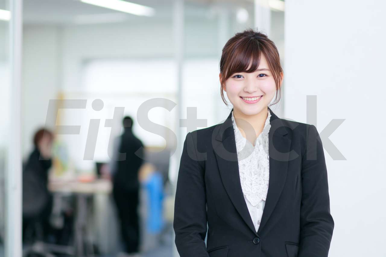オフィスで微笑むスーツ姿の若手日本人女性