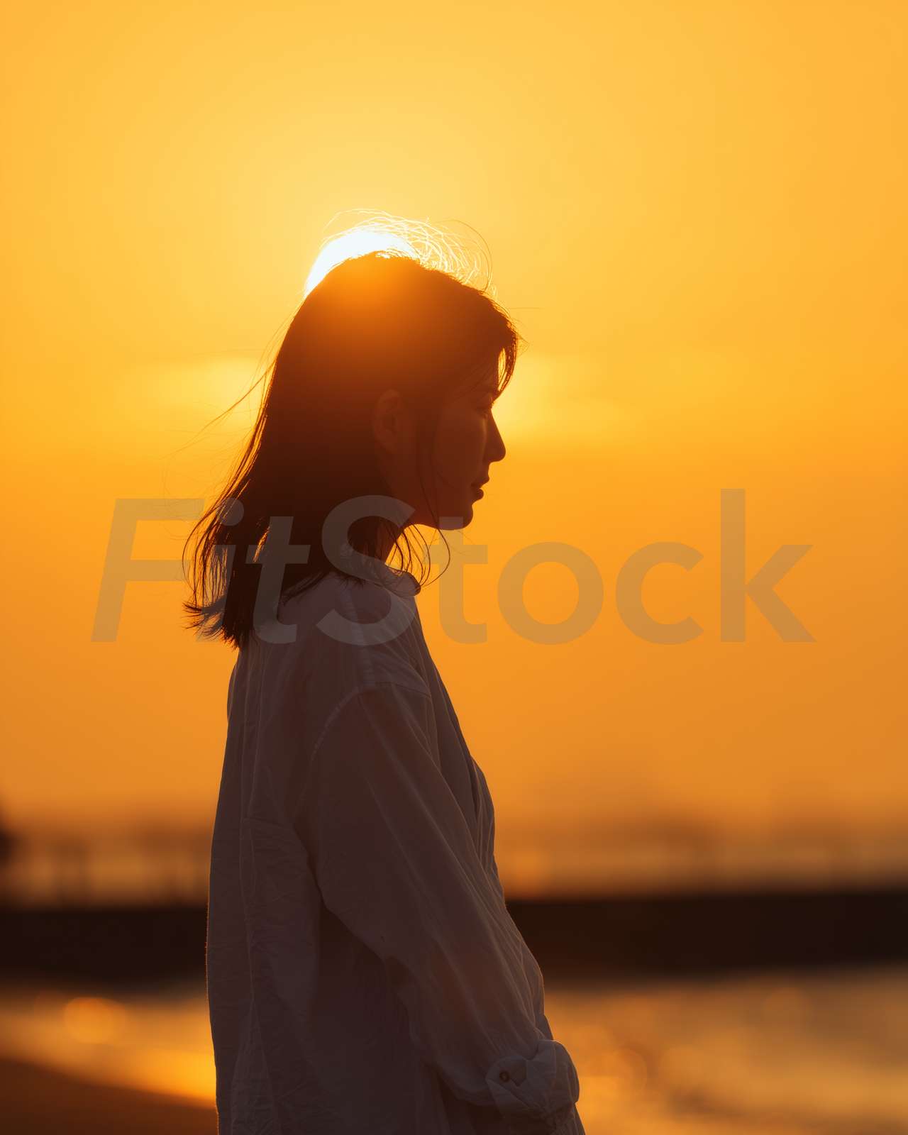 夕日を背景に佇む女性の横顔シルエット