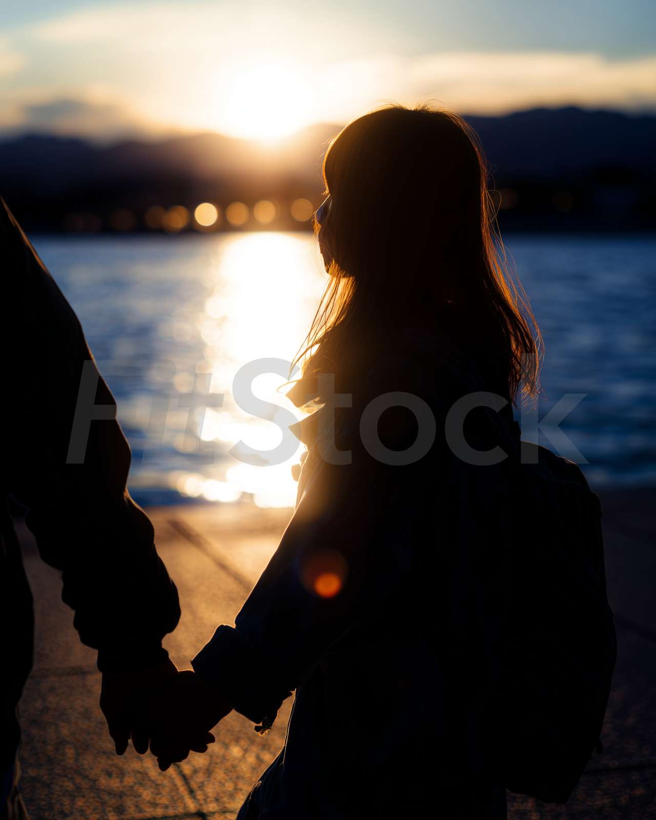 夕日を背景に手をつなぐ二人のシルエット