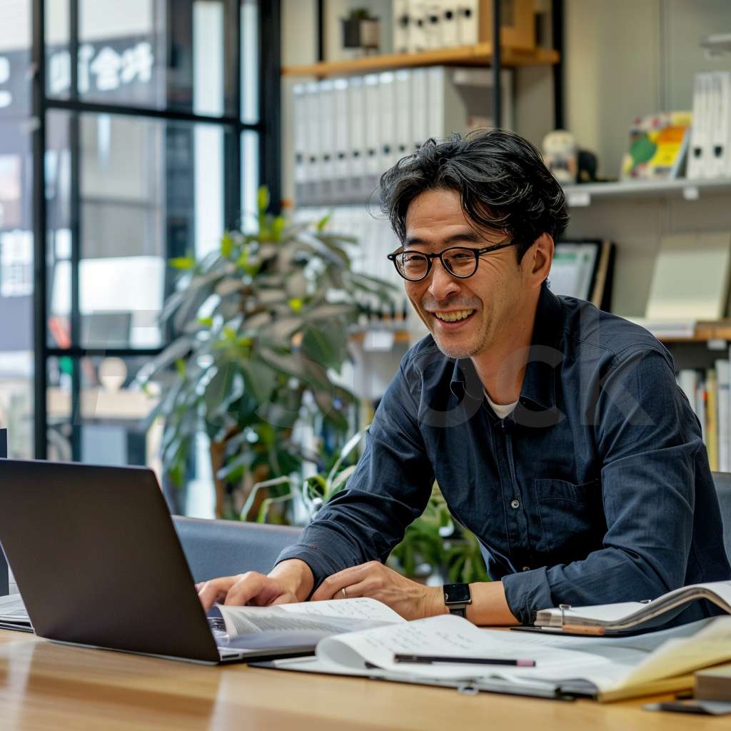 オフィスでPC作業をする笑顔の日本人男性