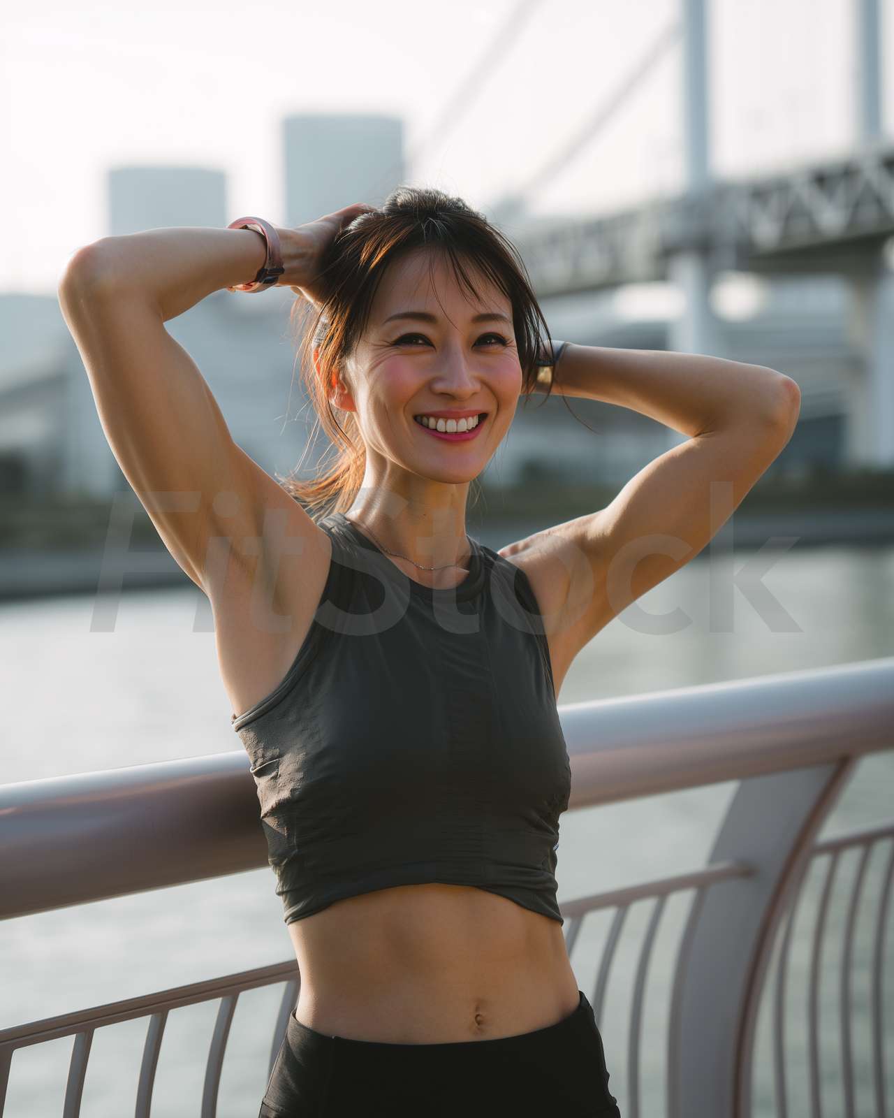 都会の橋の上で爽やかに微笑む健康的な女性