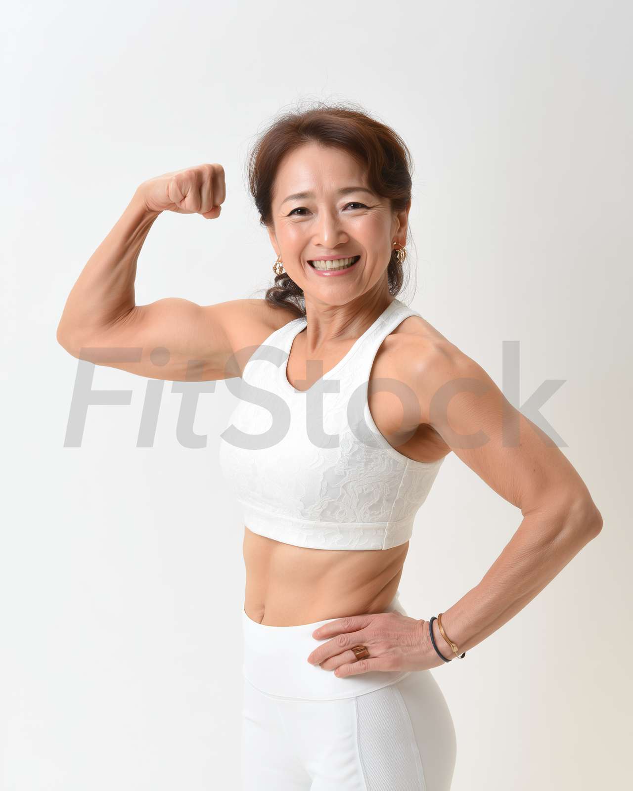 力こぶを作り笑顔でポーズをとる健康的な中高年女性