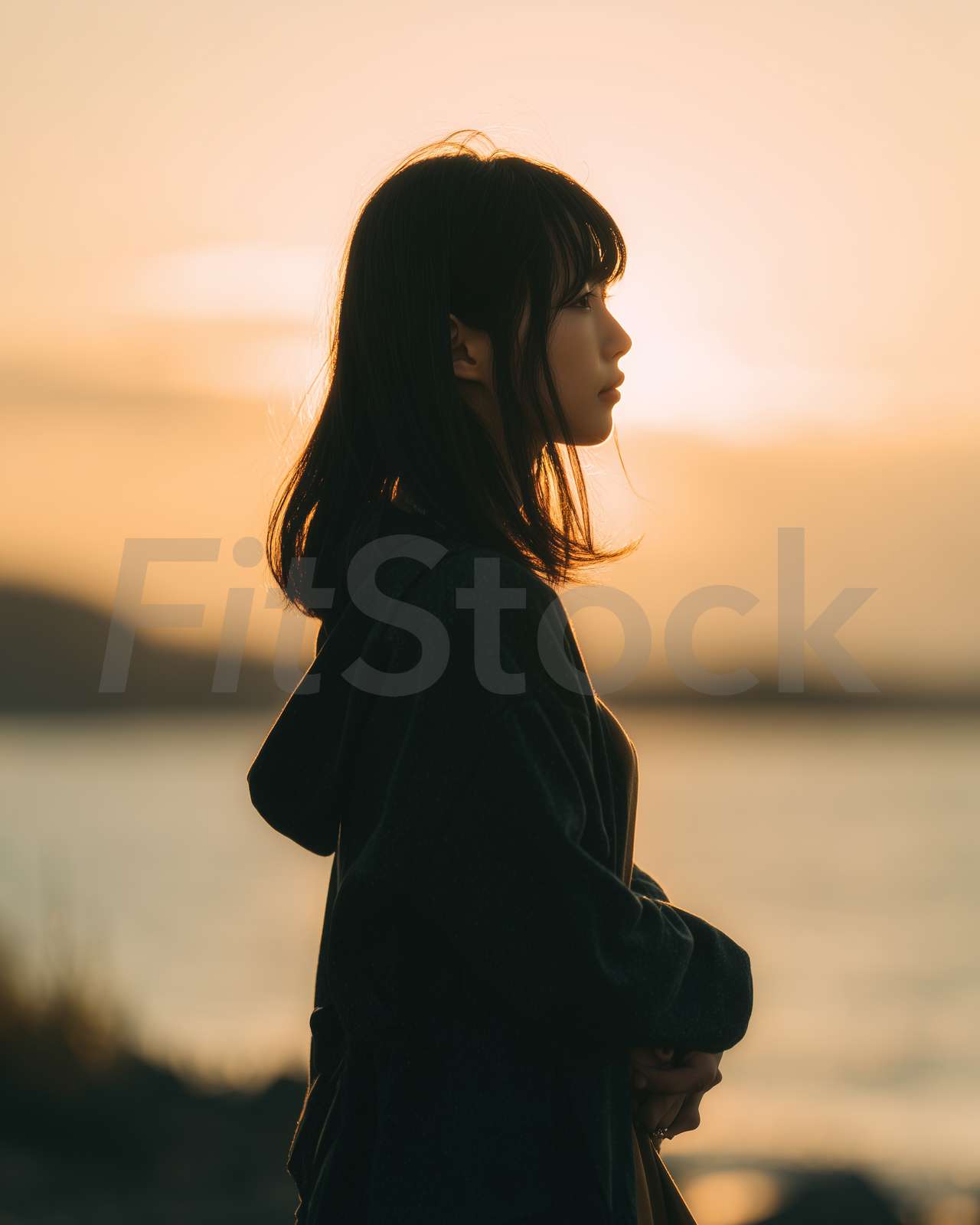 夕暮れの海辺で物思いにふける女性