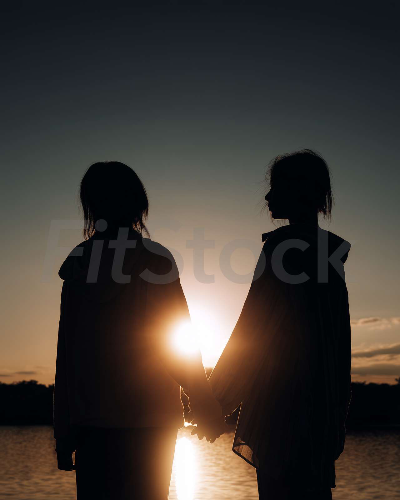 夕暮れ時に手を取り合う二人のシルエット