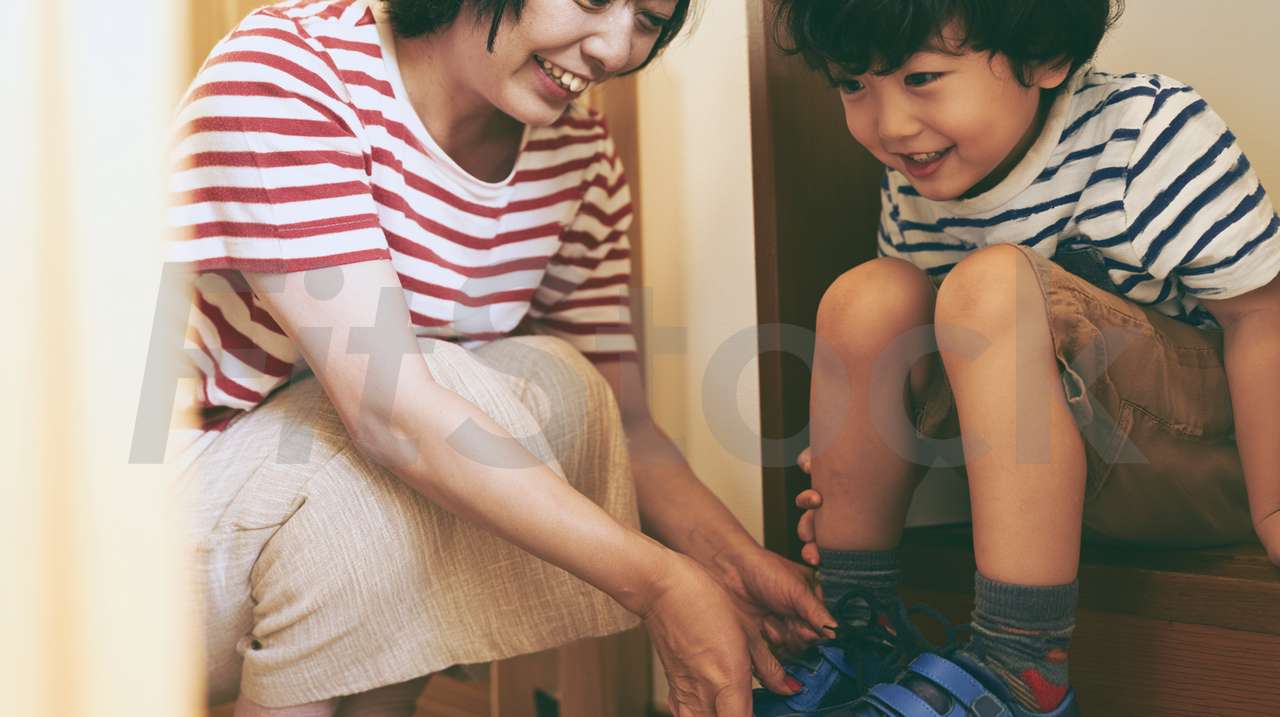 子供の靴を履かせる母親