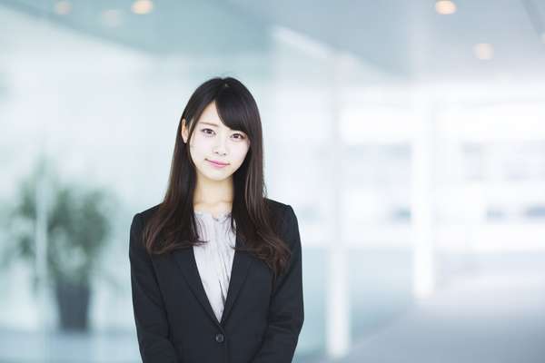 オフィスで微笑むスーツ姿の若い日本人女性