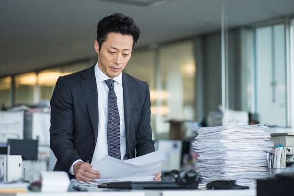 オフィスで書類を確認するスーツ姿の日本人ビジネスマン