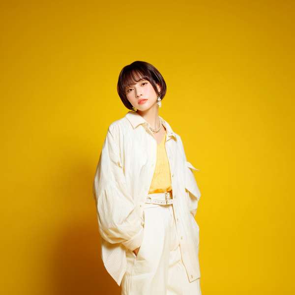 黄色い背景でポーズをとるショートヘアの女性