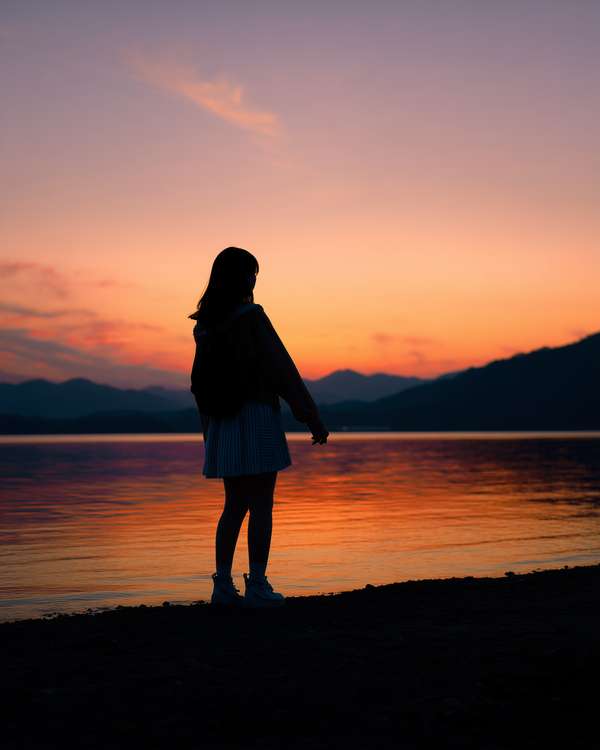 夕暮れの湖畔に佇む少女のシルエット