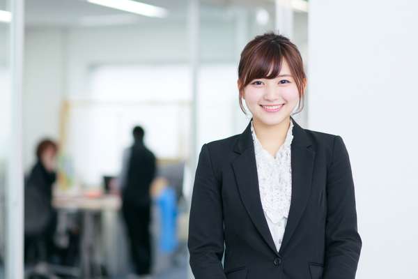 オフィスで微笑むスーツ姿の若手日本人女性