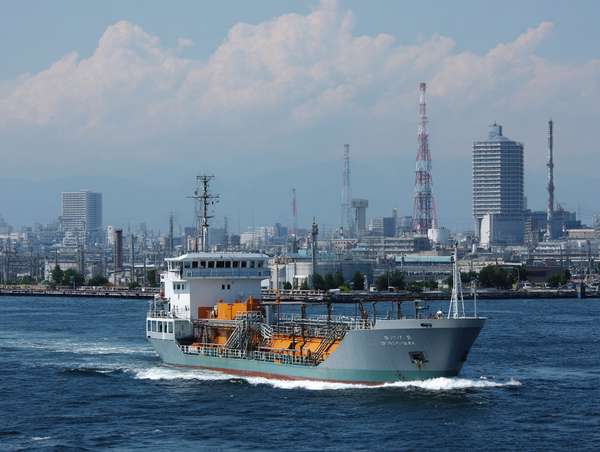 工業地帯の海を進む貨物船