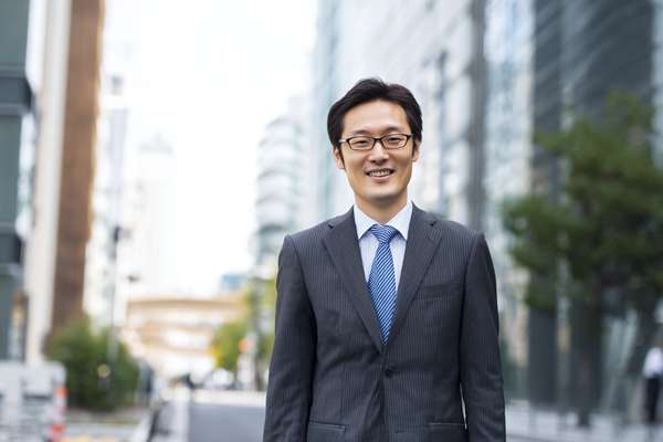 都会のオフィス街で微笑むビジネスマン