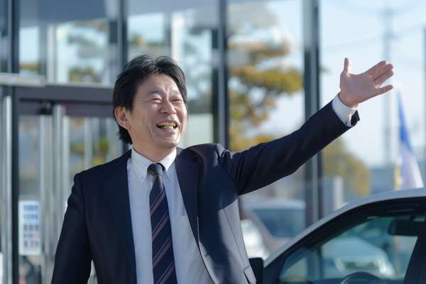 笑顔で手を振る自動車ディーラーの男性