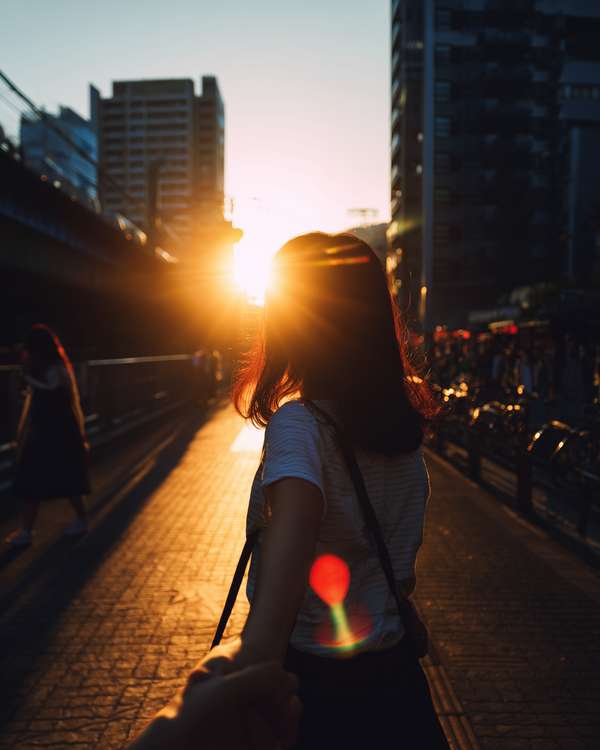 夕暮れの街で手を引く女性のシルエット