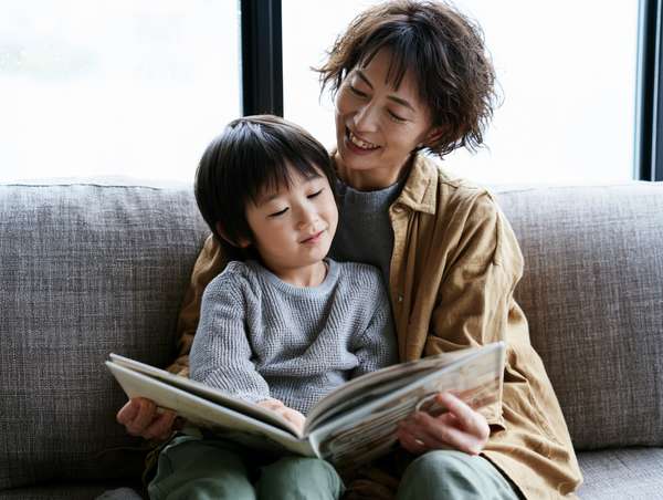 ソファで絵本を読む親子の微笑ましい姿