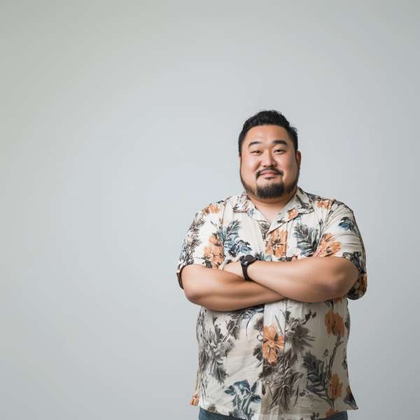 腕を組んで微笑むアロハシャツを着たアジア人男性