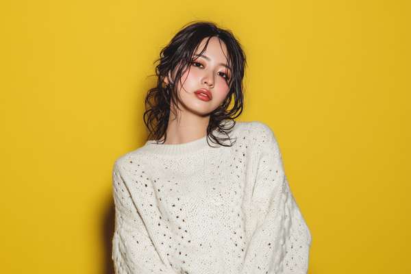 黄色い背景に白いニットを着た女性のポートレート