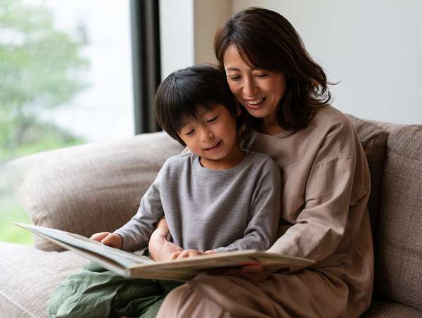 ソファで絵本を読む母と子