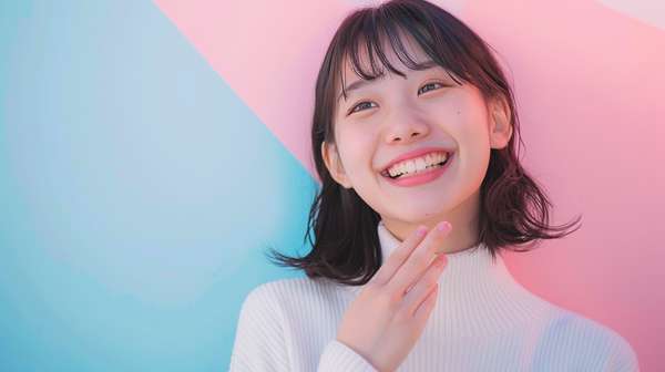 青とピンクの背景で微笑む若い日本人女性