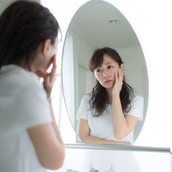 鏡を見て肌の悩みを抱える女性