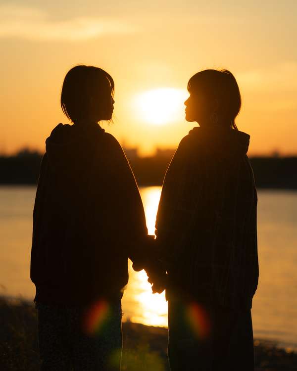 夕暮れ時に手をつなぐ二人の女性のシルエット