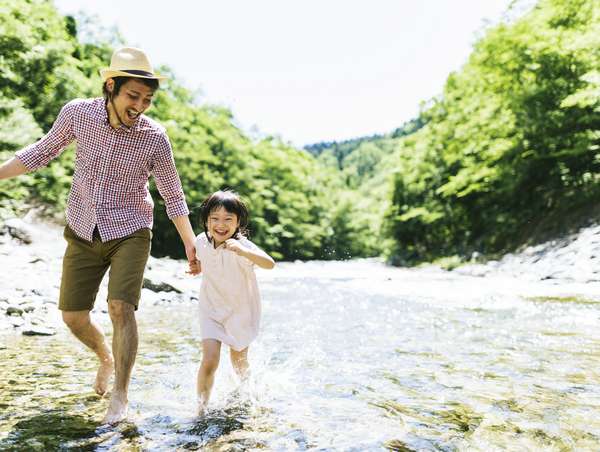 川で楽しく水遊びをする親子