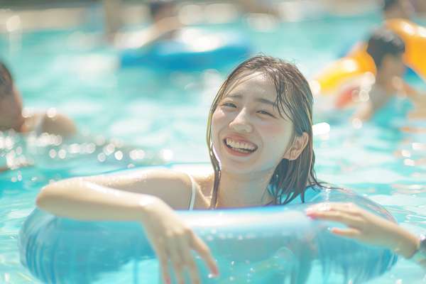 プールで浮き輪に乗って笑顔の女性
