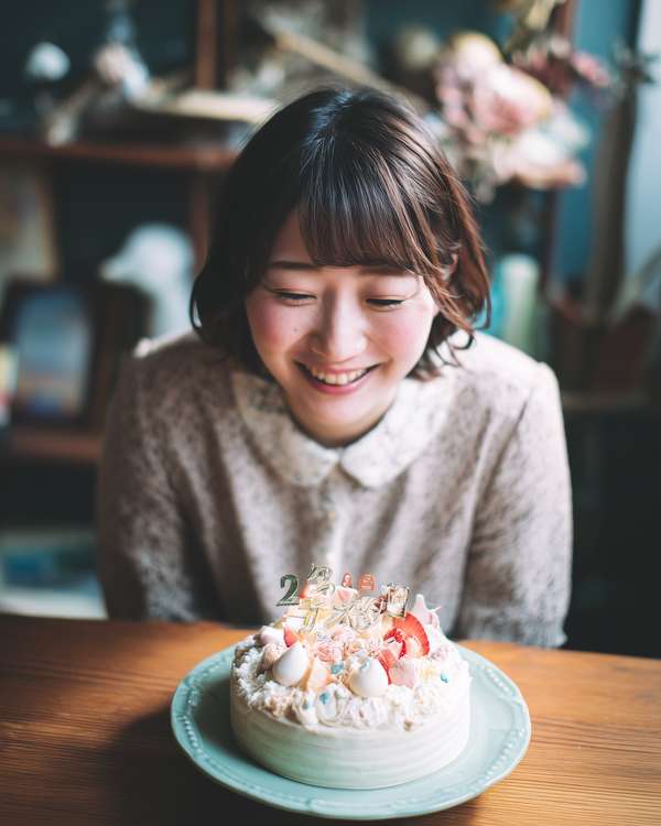 誕生日ケーキを見つめて微笑む女性