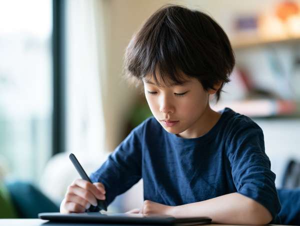 ペンタブレットでイラストを描く集中した少年の横顔