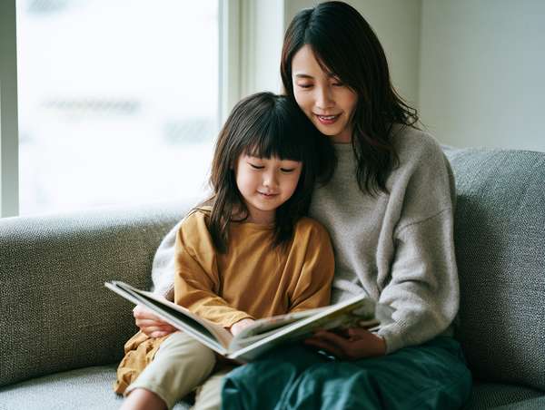 ソファで絵本を読む親子の微笑ましい姿