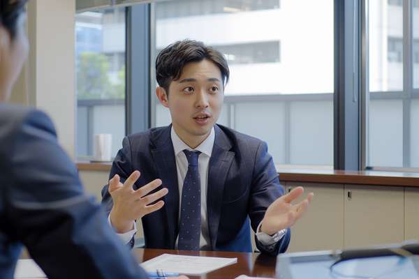 オフィスで打ち合わせをするスーツ姿の若い男性