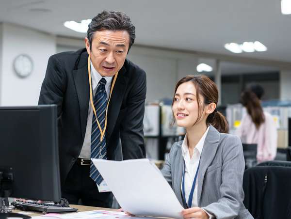 オフィスで書類を確認する上司と部下