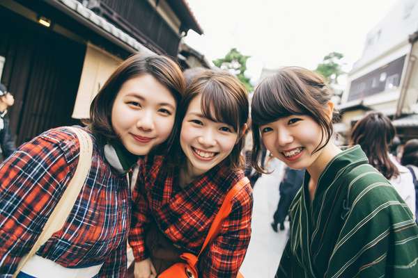 日本の街並みで笑顔を見せる仲良し三人組の女性たち