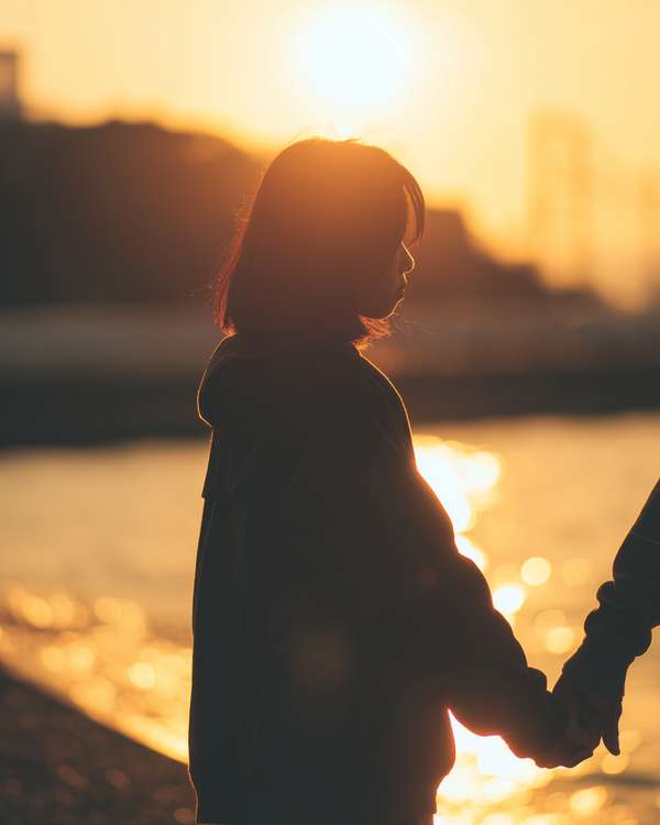 夕暮れ時に手を取り合う二人のシルエット