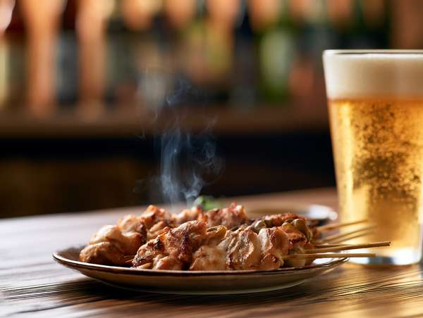 湯気が立つ焼き鳥と冷えたビール