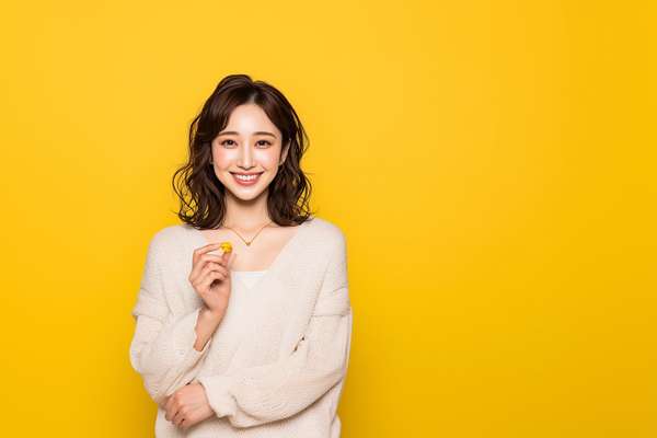 黄色の背景で笑顔を見せる若い女性のポートレート