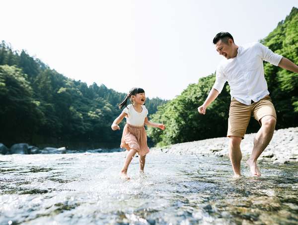 川で水遊びを楽しむ父と娘