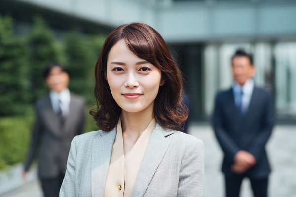 オフィス街で微笑む若手女性ビジネスパーソン