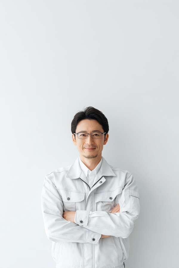腕組みをして微笑む作業服の男性