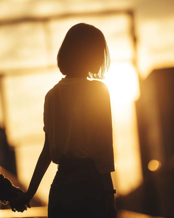 夕暮れ時に手をつなぐ女性のシルエット