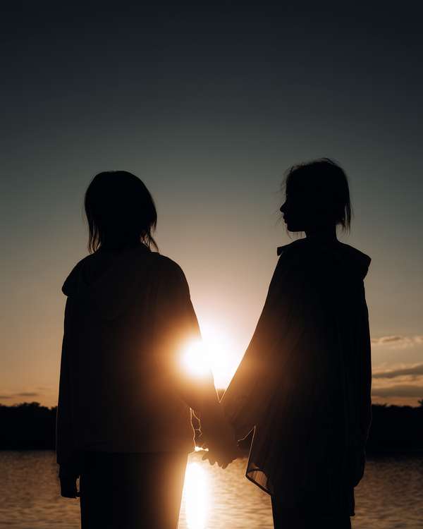 夕暮れ時に手を取り合う二人のシルエット