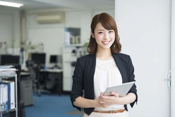 オフィスでタブレットを持つ笑顔の女性