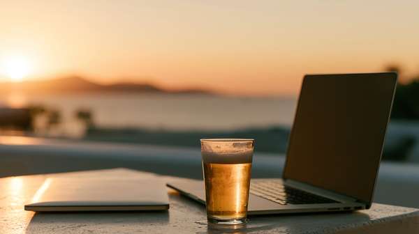 夕暮れの海辺でビールを片手にリモートワーク