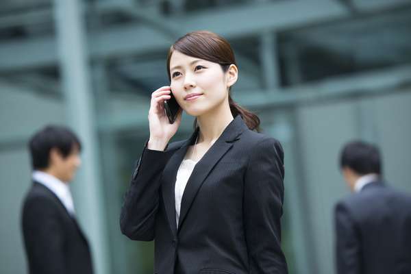 ビジネス街でスマートフォンを使って通話する日本のビジネスウーマン