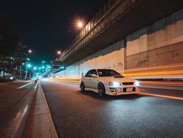 夜の街を疾走する白いスポーツカー
