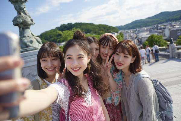 晴れた日に屋外で自撮りを楽しむ女子グループ