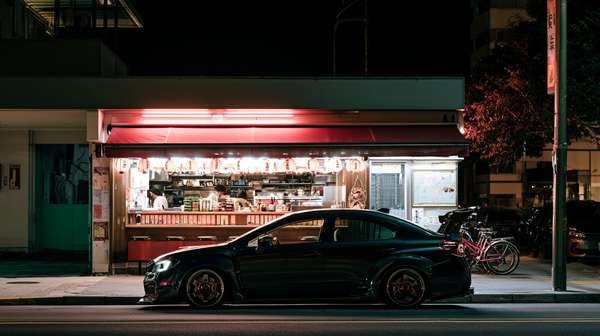 夜の屋台前に駐車されたスポーツカー