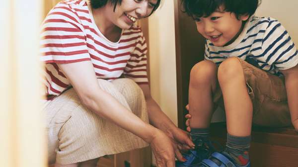 子供の靴を履かせる母親