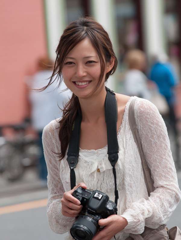 カメラを持って微笑む明るい雰囲気の若い女性