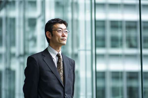 ビジネス街で視線を遠くに向けるスーツ姿の日本人男性